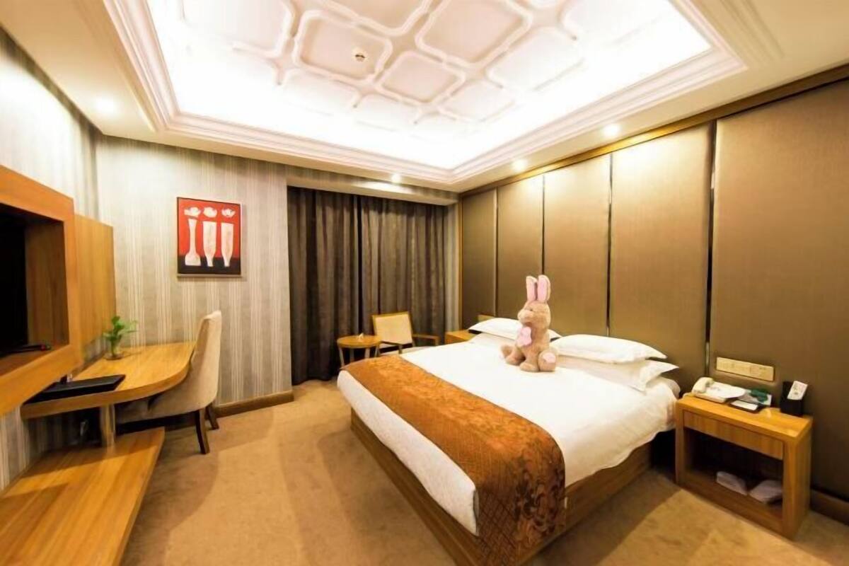 Ein Hotelzimmer mit Bett, Schreibtisch, Stuhl, Fernseher und Nachttisch.