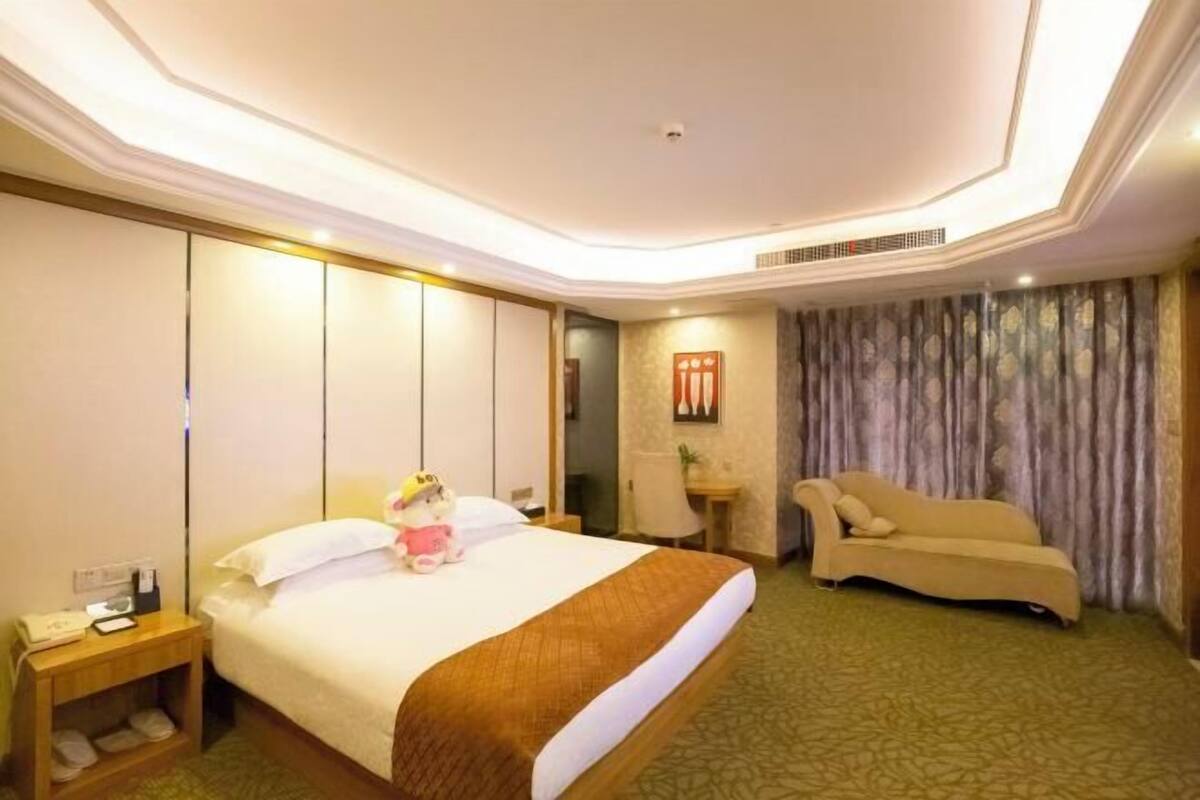 Ein Hotelzimmer mit einem großen Bett, einer Sitzecke mit einer Couch, einem Schreibtisch und einem kleinen Tisch.