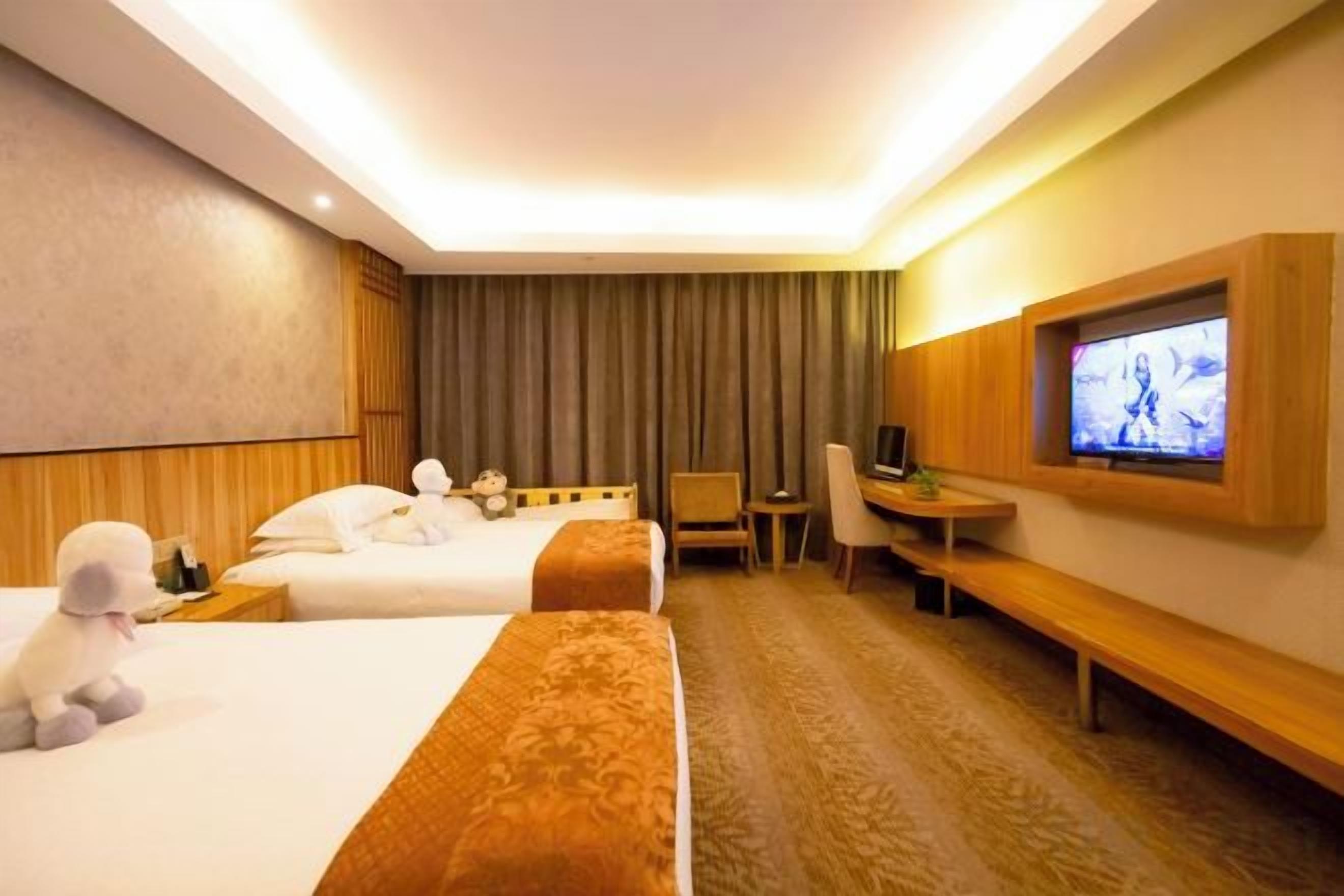 Habitación de hotel con dos camas, un escritorio, un televisor y una zona de estar.