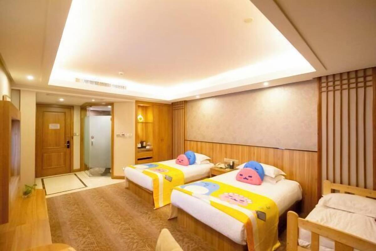 Ein Hotelzimmer mit zwei Betten, einem Holzkopfende, einem kleinen Nachttisch und einem Teppichboden.