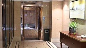 A hotel lobby with a reception desk, a potted plant, a trash bin, and a door leading to another room. - Siji Yucheng Boutique Hotel (Anji Jiuzhou Shopping Mall) (Anji)