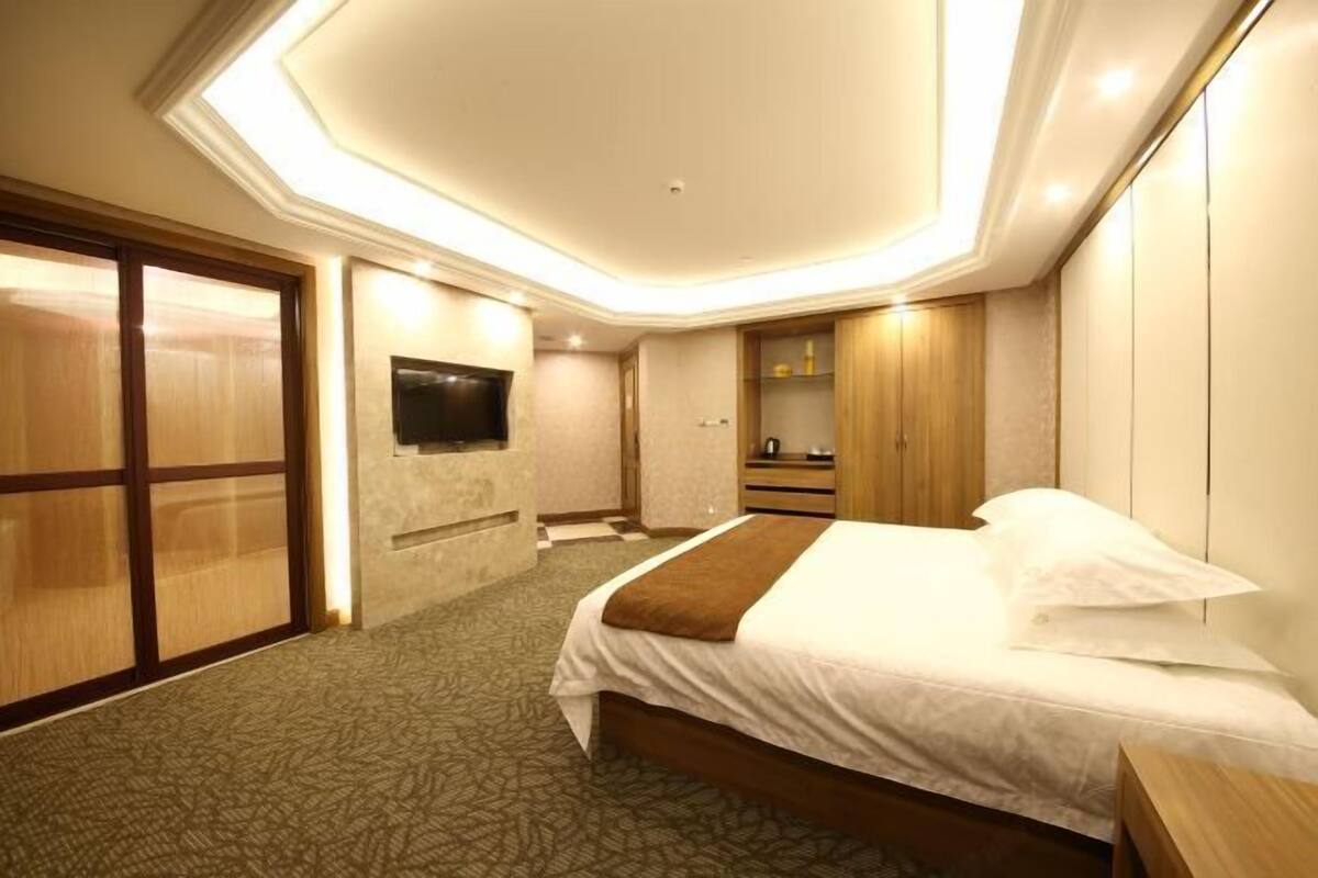 Ein Hotelzimmer mit Bett, Fernseher, Holzschrank und Bad.