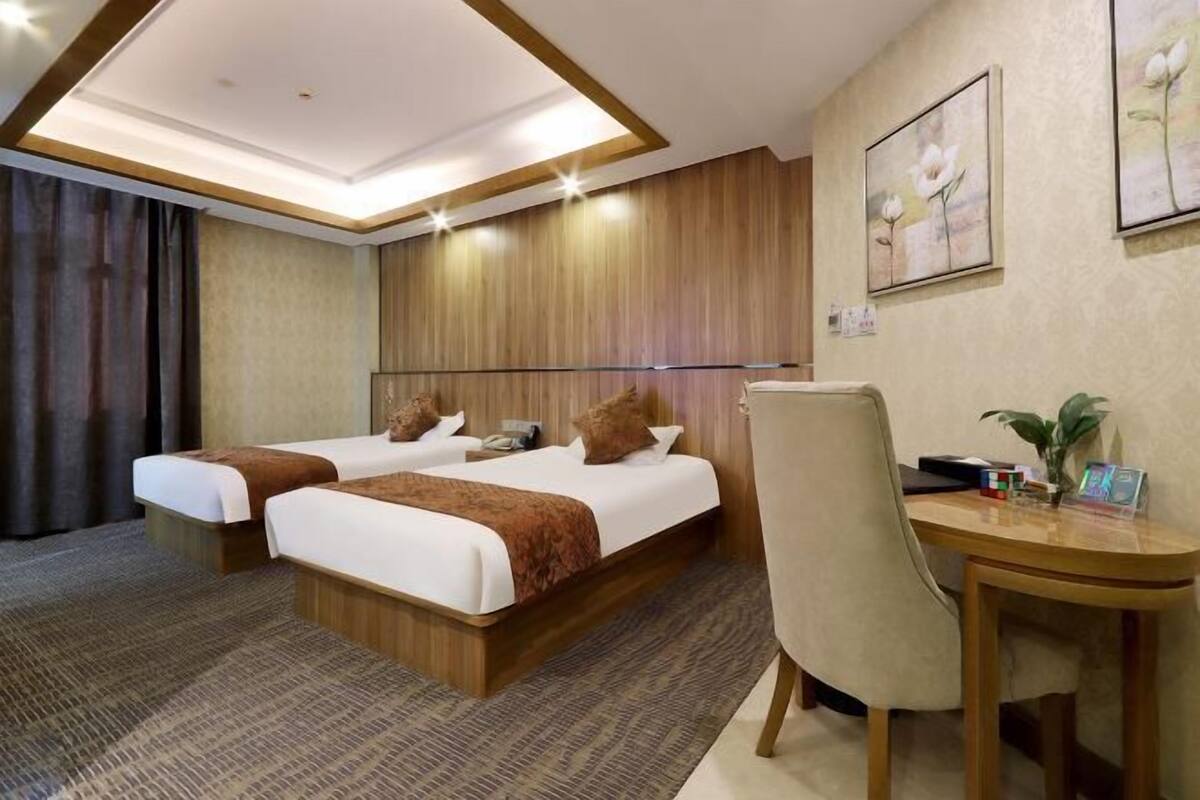 Ein Hotelzimmer mit zwei Betten, einem Schreibtisch und einem Stuhl.
