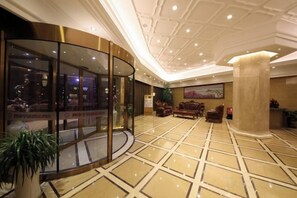 Un hall d’entrée doté d’un mur en verre incurvé, d’une grande colonne et d’un espace détente avec des canapés.