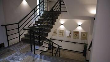 A staircase with a handrail, wall-mounted lighting, and framed pictures.