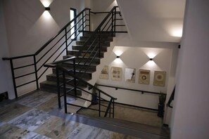 Una scala con corrimano, illuminazione a parete e quadri incorniciati.