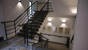 A staircase with black railings and a handrail, leading to a landing with framed certificates on the wall. - Heyou Cisheng Life Class Health Resort Hotel (Shanghai)
