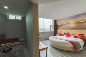 Una habitación de hotel con una cama, un escritorio, una mesita y un cuadro en la pared.