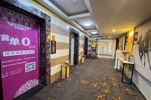 A hotel corridor with a patterned floor, a reception desk, and a wall with a QR code. - Kaili New Century Hotel (Grand Cross of International Trade Shopping Center) (Kaili)