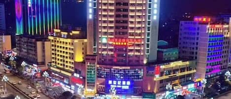 A multi-story hotel with a central atrium, surrounded by other buildings with illuminated signage.