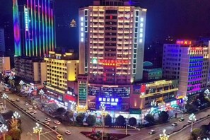 Hotel de varios pisos con un atrio central, rodeado de edificios con señalización iluminada.