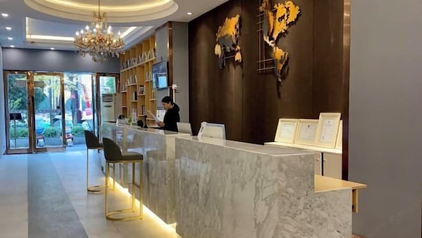 A hotel reception area with a marble counter, a chandelier, and a wall-mounted map. - Kaili New Century Hotel (Grand Cross of International Trade Shopping Center) (Kaili)
