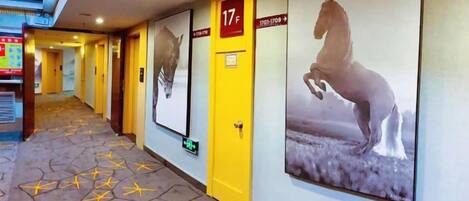 A hotel corridor with doors marked 17F and 17G, posters of horses, and a patterned floor.
