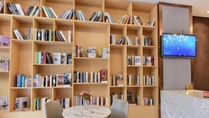 A library with bookshelves, a reception desk, and two chairs. - Kaili New Century Hotel (Grand Cross of International Trade Shopping Center) (Kaili)
