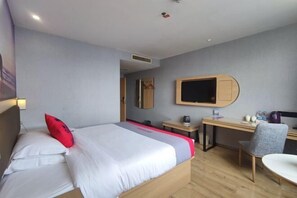 Una habitación de hotel con cama, escritorio, silla, televisor y espejo.