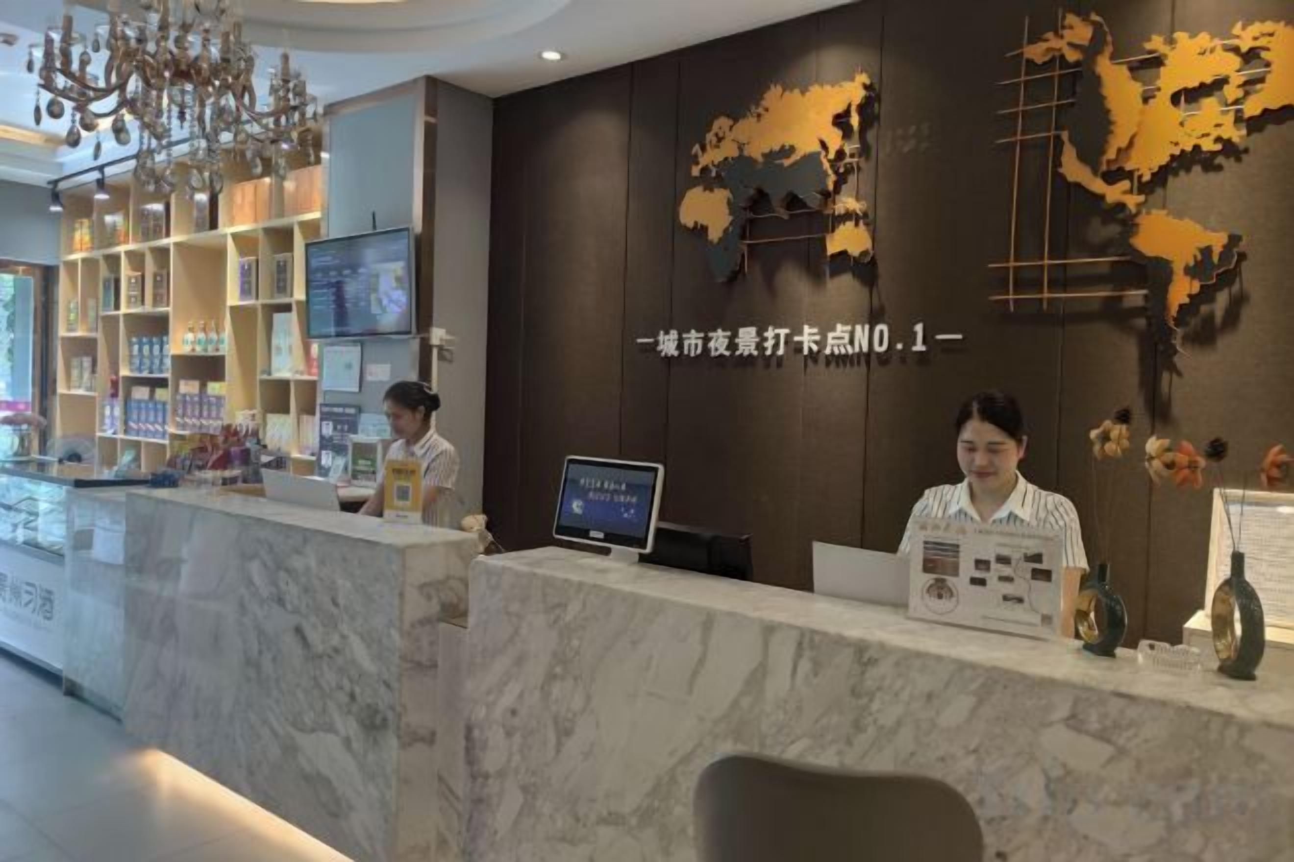 A hotel reception desk with a marble counter, a digital screen, and a wall with a world map design.