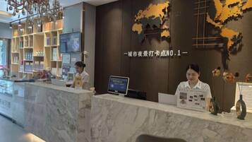 A hotel reception desk with a marble counter, a digital screen, and a wall with a world map design.
