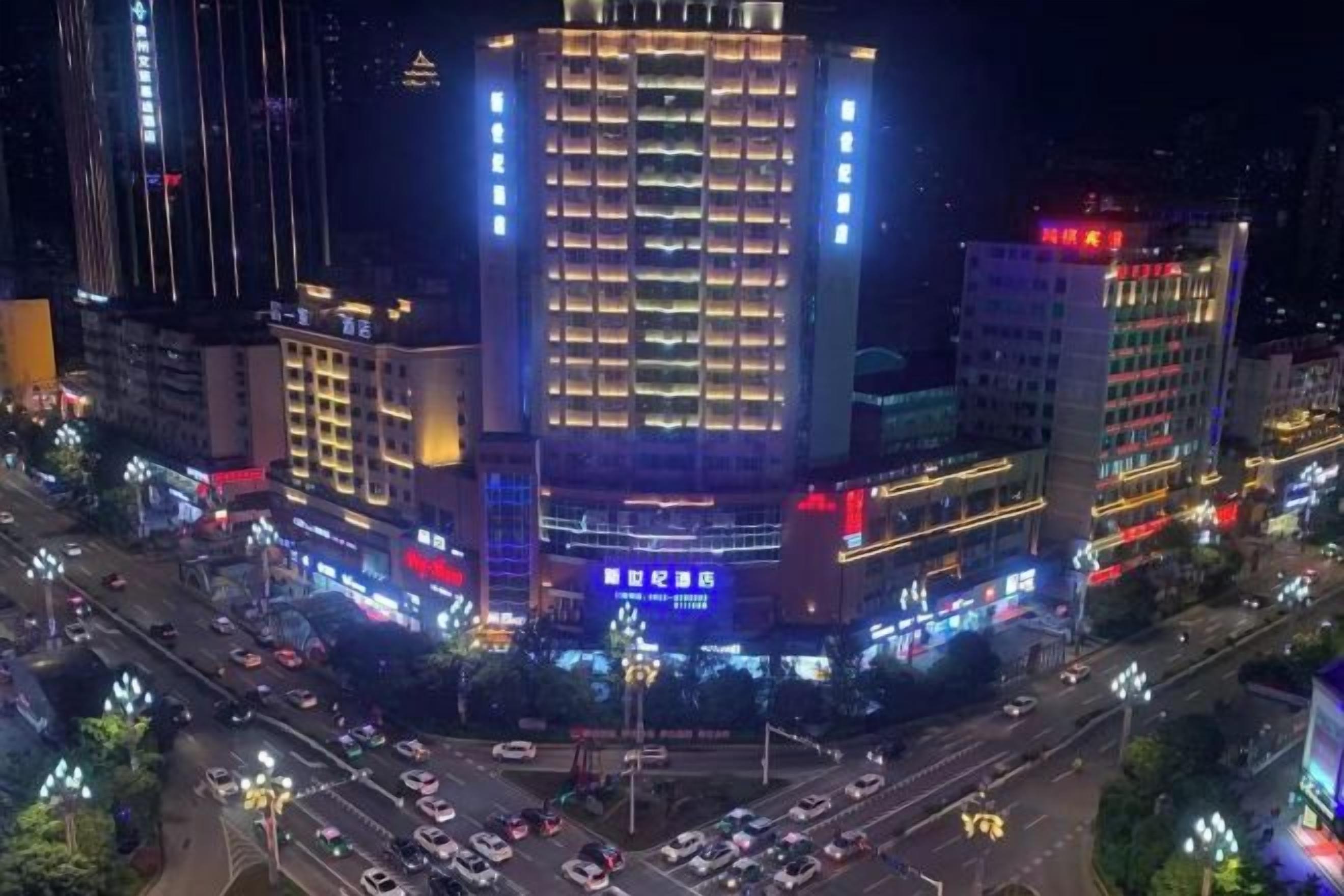 A multi-story building with illuminated signage and a busy intersection below.