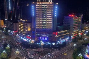 A multi-story building with illuminated signage and a busy intersection below. - Kaili New Century Hotel (Grand Cross of International Trade Shopping Center) (Kaili)