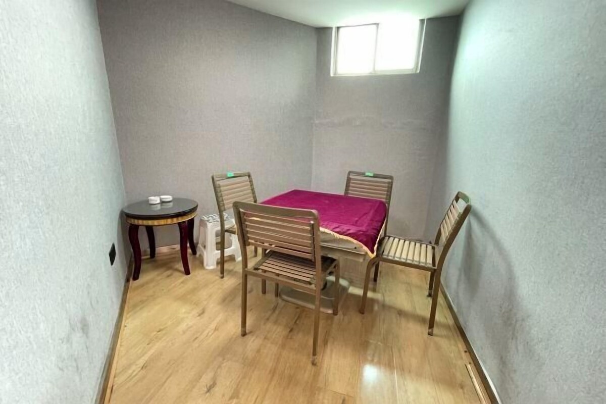 A small room with a table and four chairs, a small round table, and a window.