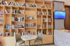Una biblioteca con estanterías, un mostrador de recepción y dos sillas.