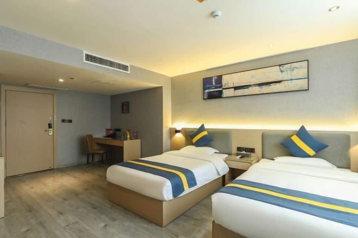 Habitación de hotel con dos camas, un escritorio y una silla.