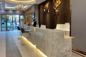 A reception area with a marble counter, bar stools, a chandelier, and a wall-mounted display. - Kaili New Century Hotel (Grand Cross of International Trade Shopping Center) (Kaili)