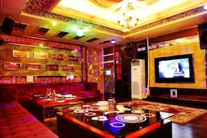 A room with a television, a sofa, a coffee table, and a patterned wall. - Saiqi Hotel (Fu'an)