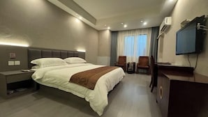 A modern hotel room with a large bed, bedside tables, a desk, a chair, and a TV mounted on the wall. - Saiqi Hotel (Fu'an)