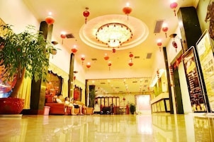 A hotel lobby with a chandelier, red lanterns, a reception desk, and seating areas.