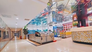 A modern indoor space with a glass ceiling, a food kiosk, and a counter with a mosaic tile design. - Saiqi Hotel (Fu'an)
