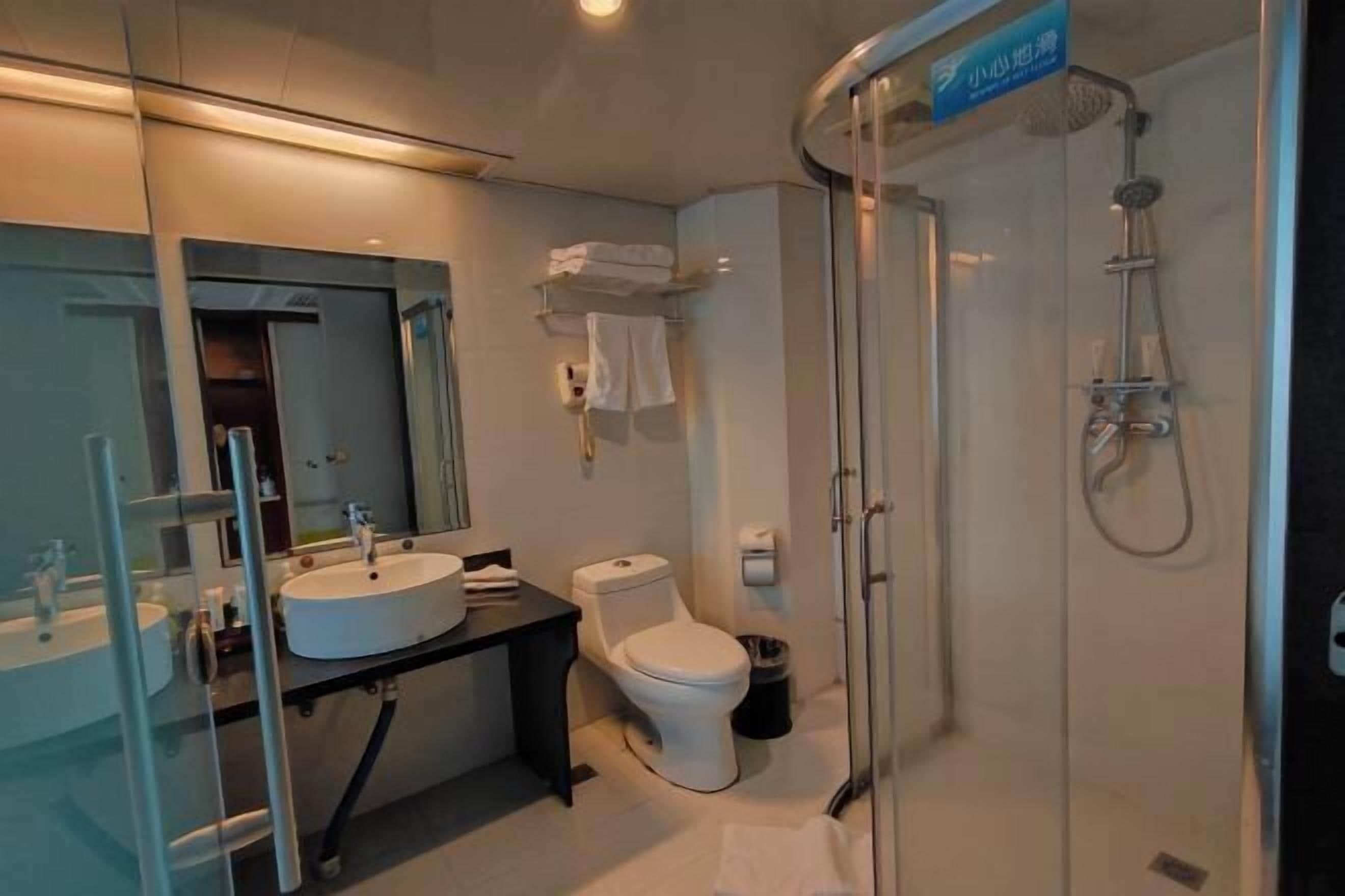 Une salle de bain moderne avec une douche à parois de verre, un lavabo blanc et des toilettes.