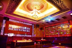 Zona de bar con techo estampado, una pantalla grande mostrando un diseño geométrico y una barra.