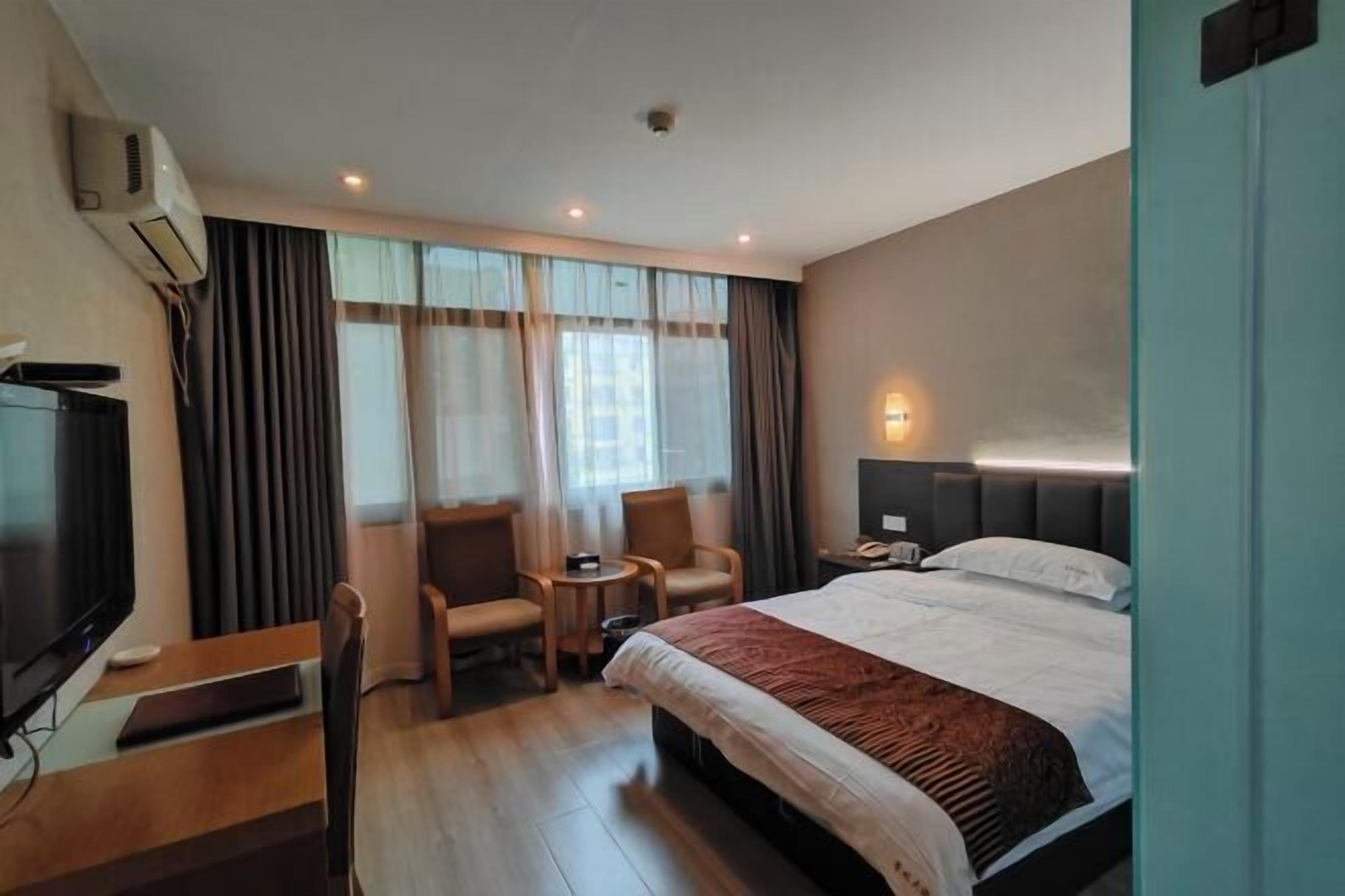 Une chambre d’hôtel avec un lit, une télévision, un bureau et une chaise.