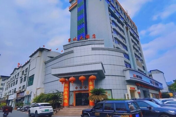 Un hotel de varios pisos con una torre destacada, una fachada curva y una entrada tradicional con faroles.