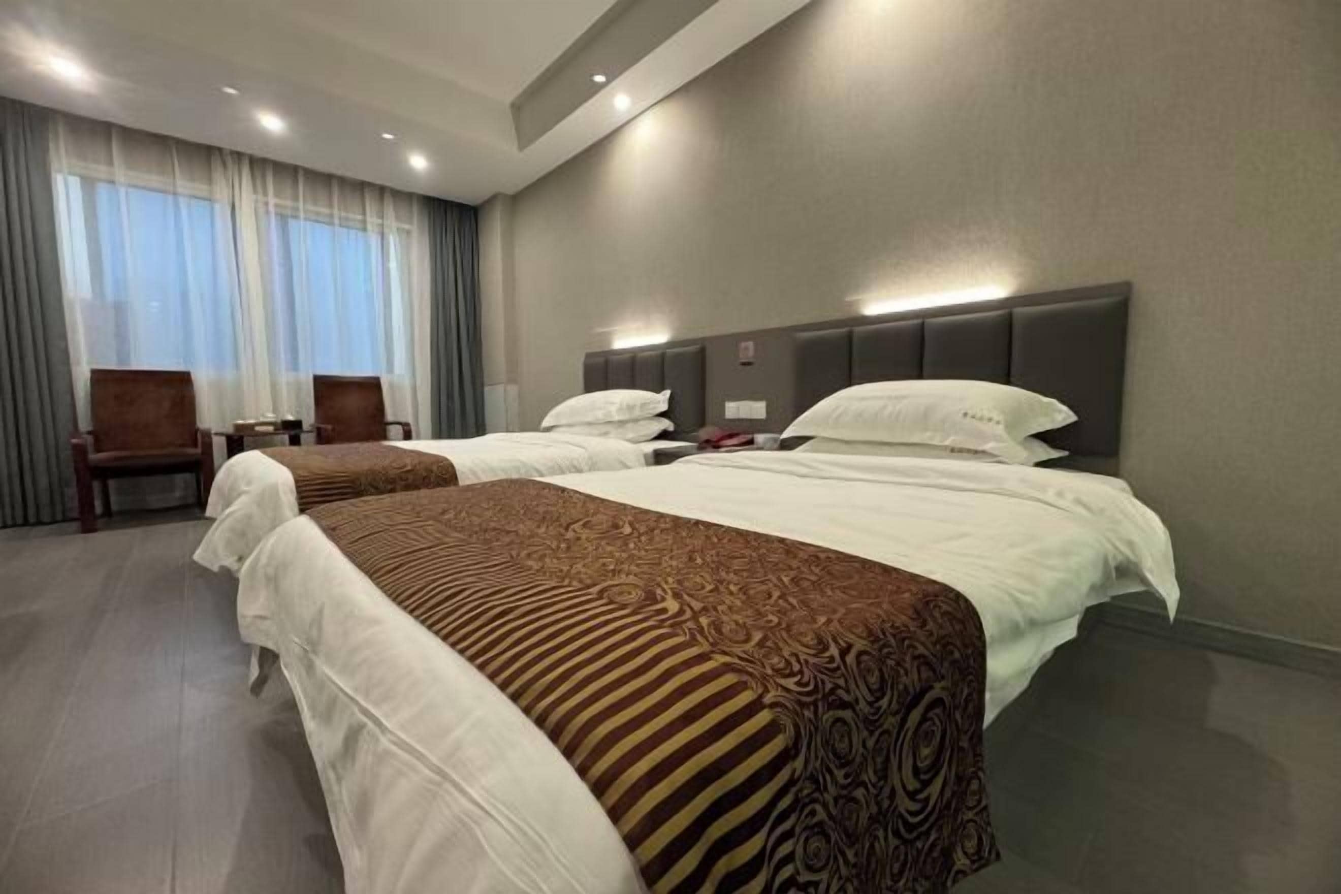 A hotel room with two beds, a desk, and a chair.
