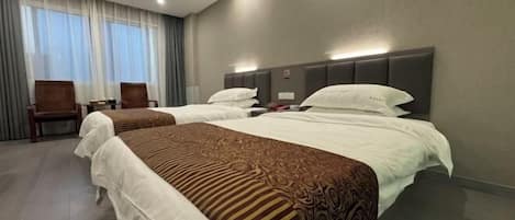 A hotel room with two beds, a desk, and a chair.