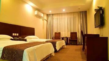 A hotel room with two beds, a desk, a chair, and a television on the wall.