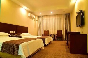 A hotel room with two beds, a desk, a chair, and a television on the wall.