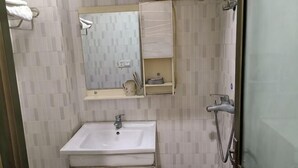 A bathroom with a sink, mirror, and shower.