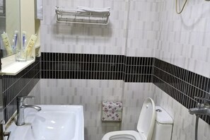 Une salle de bain avec un lavabo blanc, des toilettes et un porte-serviettes.