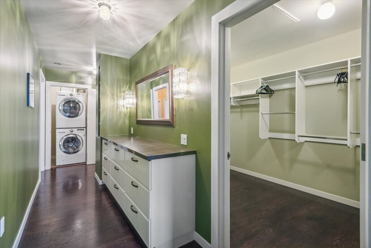 A laundry room with two washing machines, a mirror, and a storage cabinet.
