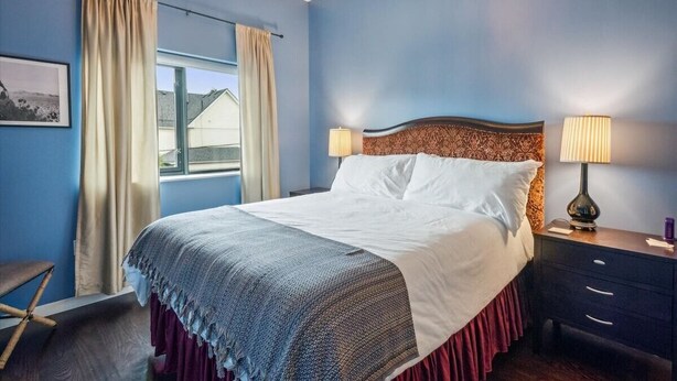 A bedroom with a bed, two bedside lamps, a window with curtains, a chair, and a framed picture on the wall. - Spacious 3BR/2BA w/ Steam Shower, Gated Parking & Full Kitchen (Portland)