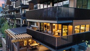 Un edificio moderno de varios pisos con asientos exteriores, piscina y balcones.