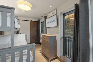A bedroom with a bunk bed, a dresser, a sign with 'VAAL BUTLER,' and a window with a view.