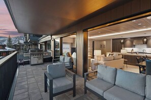 An outdoor patio with a grill, seating, and a view of the mountains.