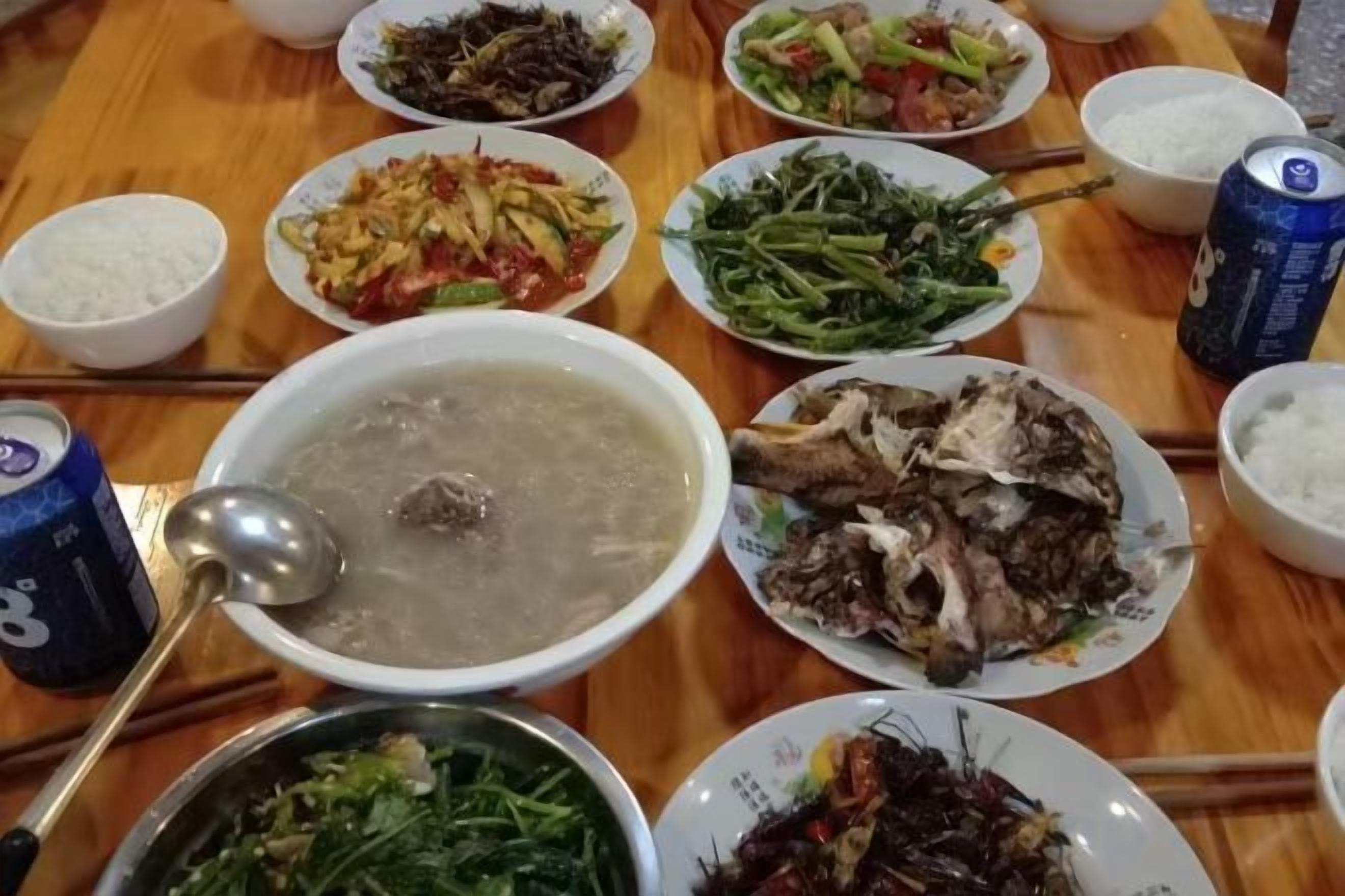 A dining table with various dishes and a can of soda.