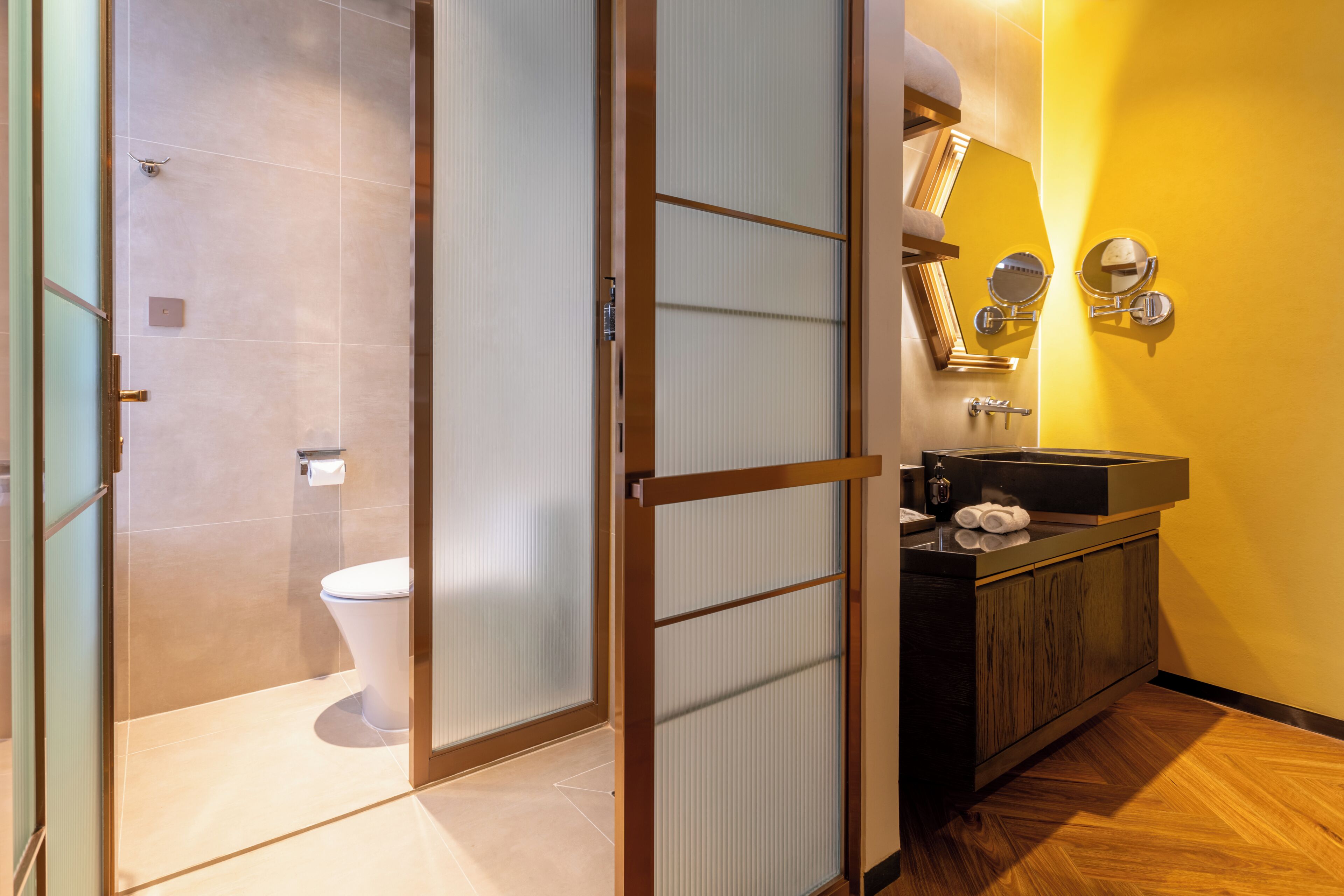 A bathroom with a toilet, a sink with a mirror, and a towel rack.