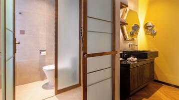 A bathroom with a toilet, a sink with a mirror, and a towel rack.