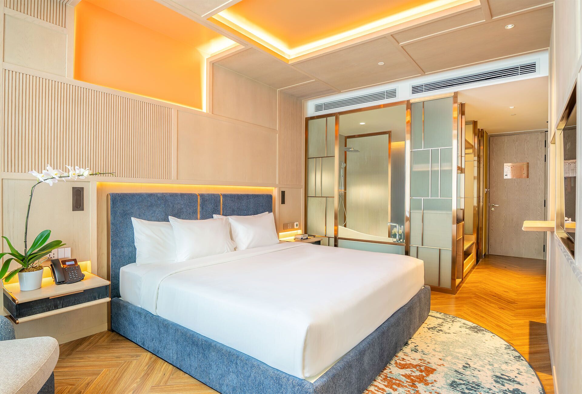 Ein modernes Hotelzimmer mit einem großen Bett, einem Nachttisch mit Telefon, einem Spiegel und einer Duschkabine.